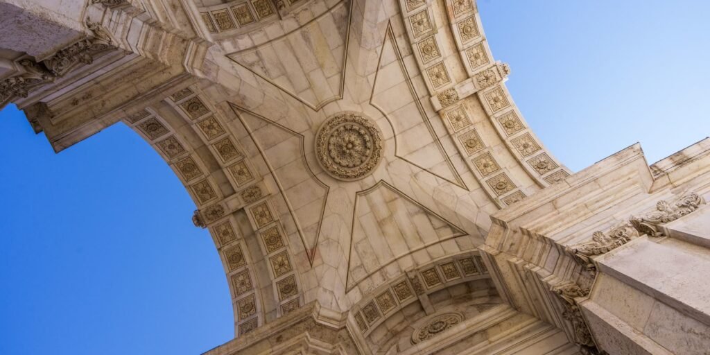Stone vault of the Rua Augusta Arch in Lisbon against a blue sky