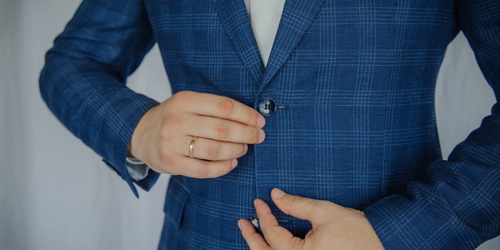 Man buttoning a navy checked tailored blazer