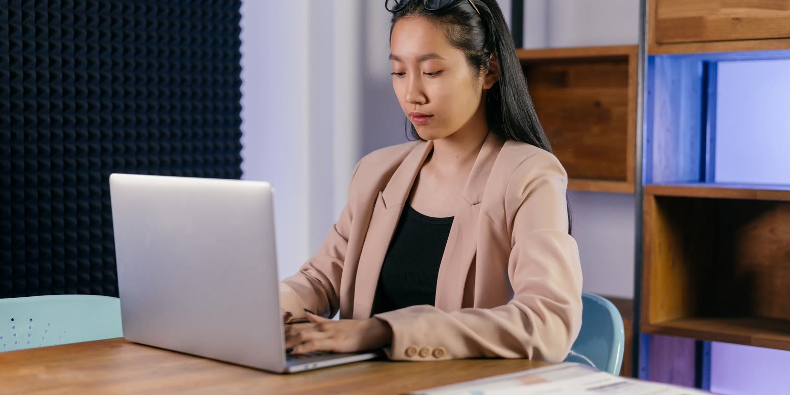 Woman in a beige blazer working on a laptop