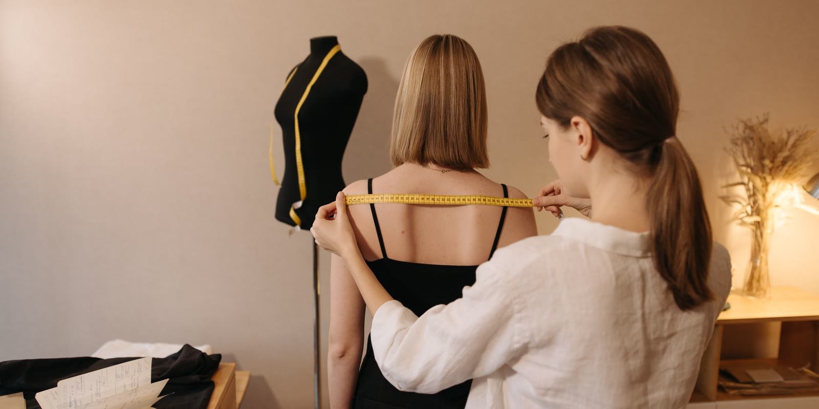 Tailor taking a client's measurements in a studio
