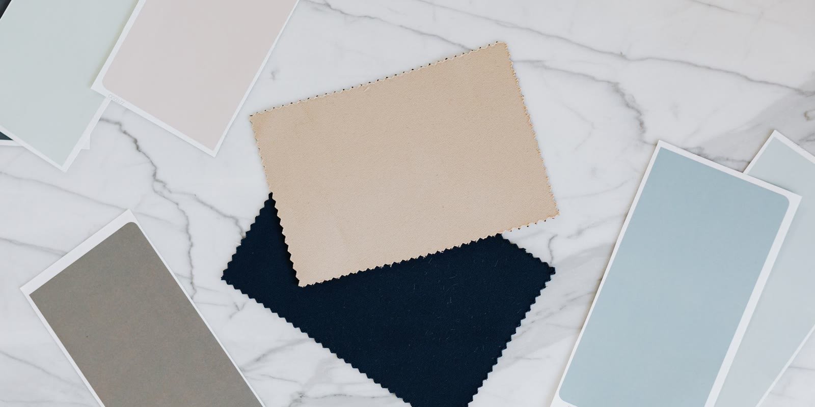 Fabric samples in neutral tones on a marble table
