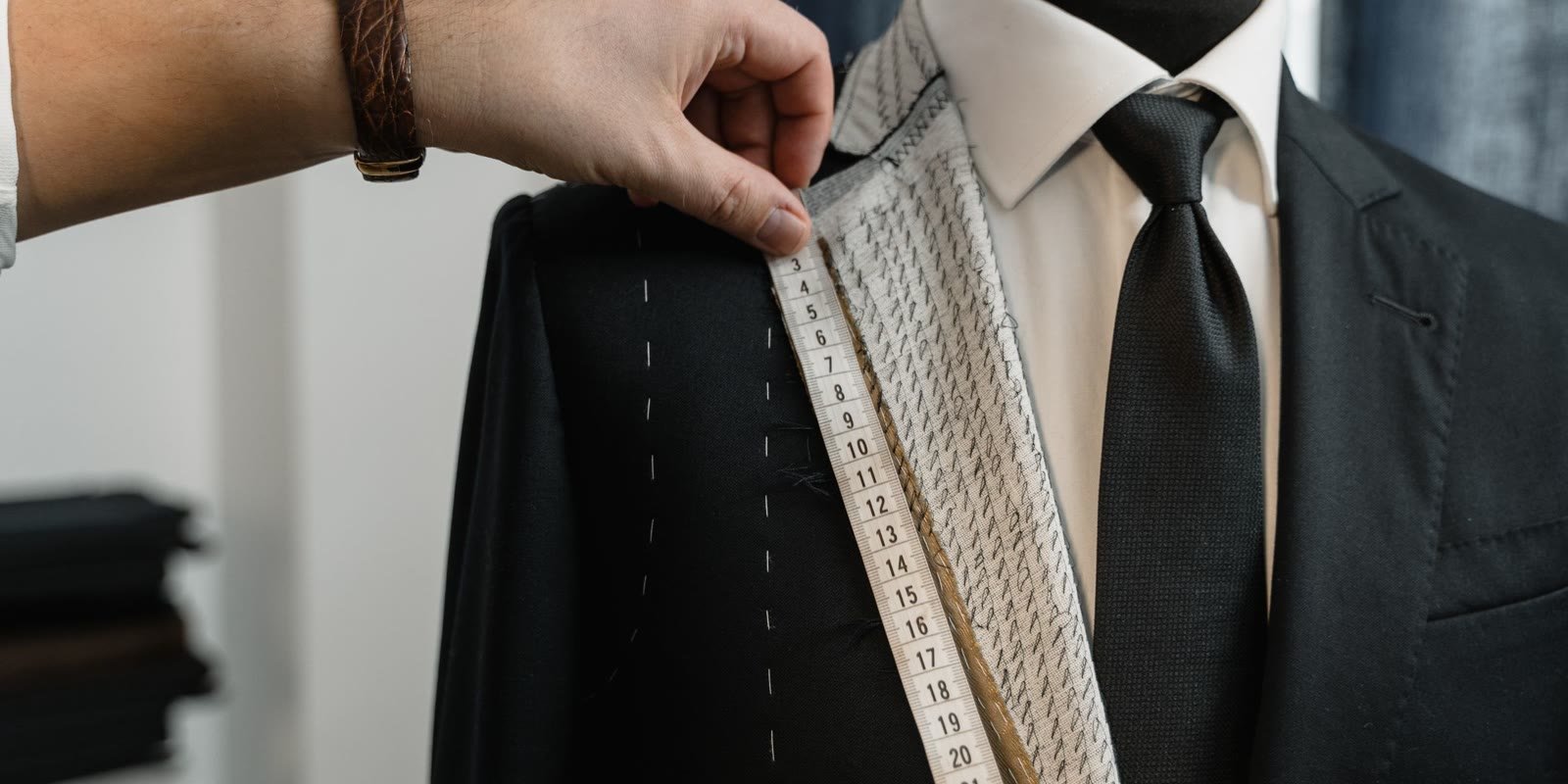 Tailor measuring the lapel of a dark suit