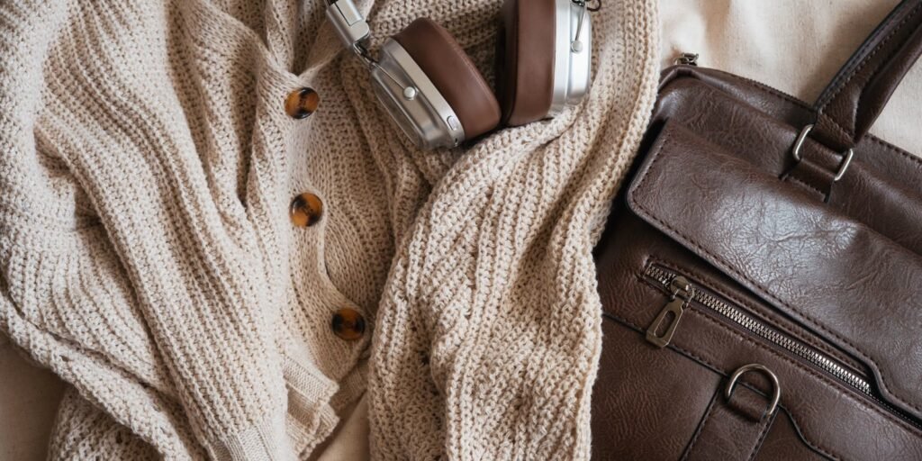 Flat lay of a cream knit, leather bag and accessories