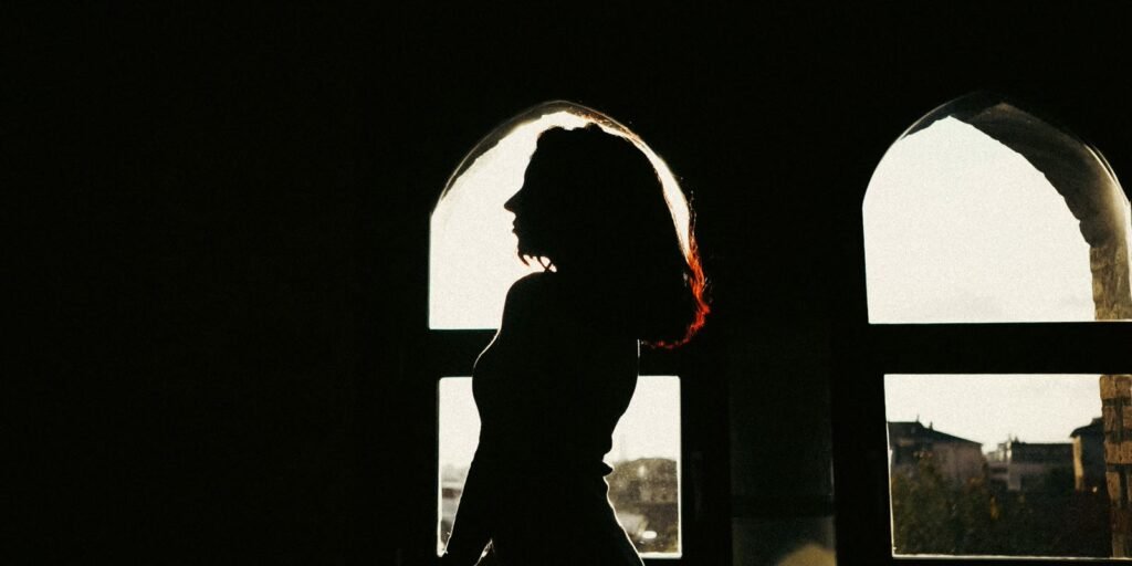 Silhouette of a woman by an arched window